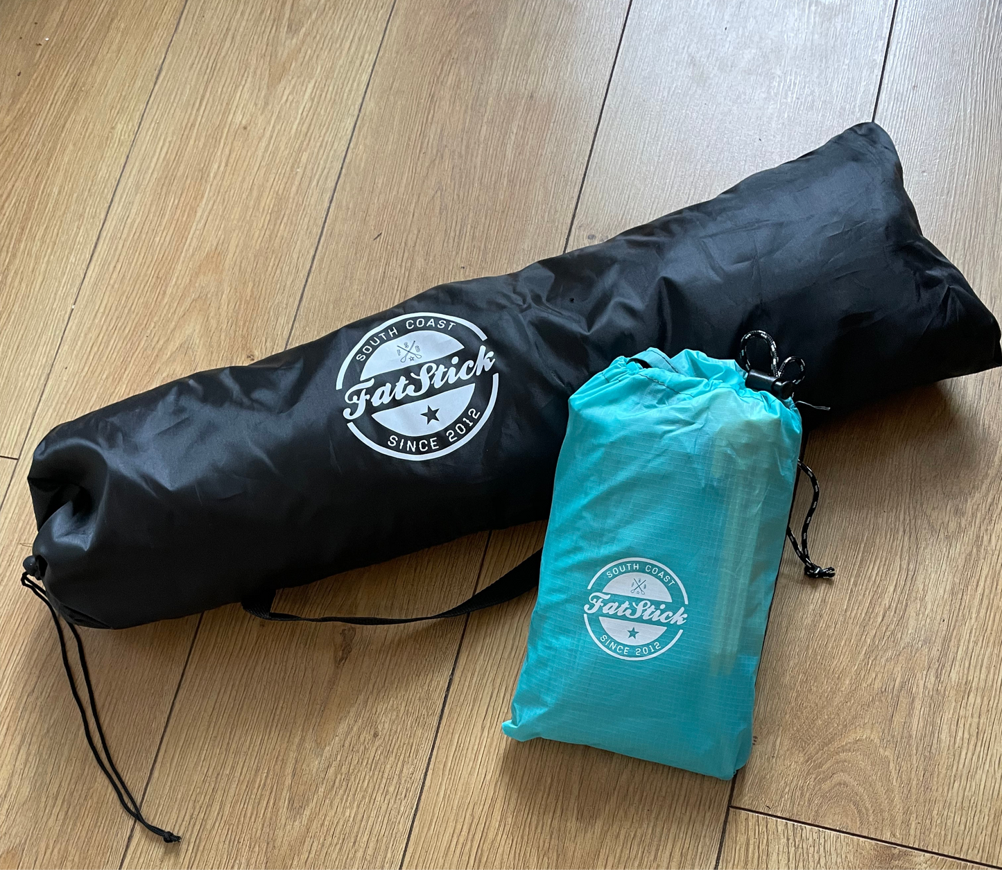 Black bag for the Fatstick Beach Tent sun shade and a smaller blue bag for ground sheet.