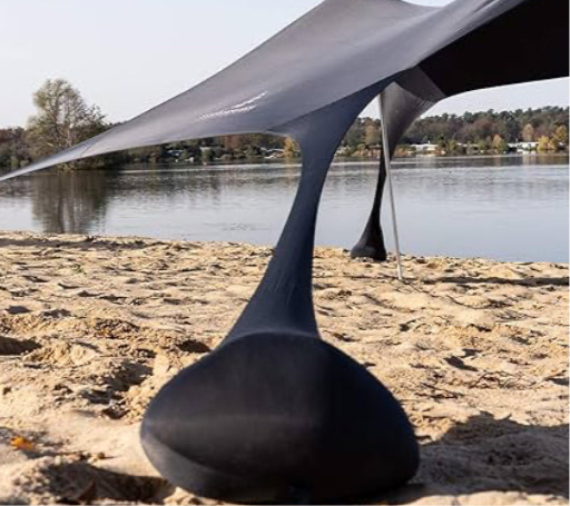 Close-up of the black Fatstick Beach Tent upright pole base on a sandy beach by a lake.