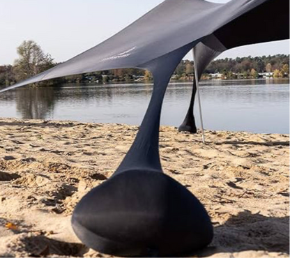 Close-up of the black Fatstick Beach Tent upright pole base on a sandy beach by a lake.