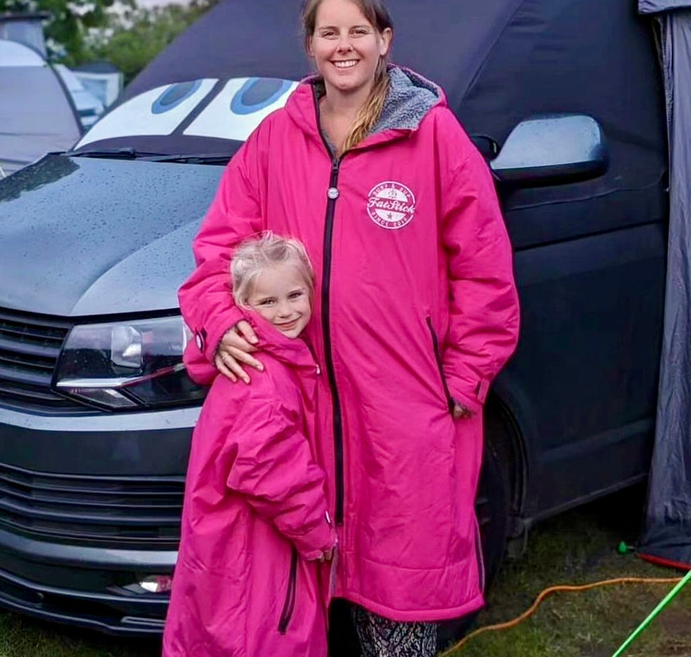 Mother and daughter wearing matching pink FatStick FatWrap changing robes, smiling, camping.
