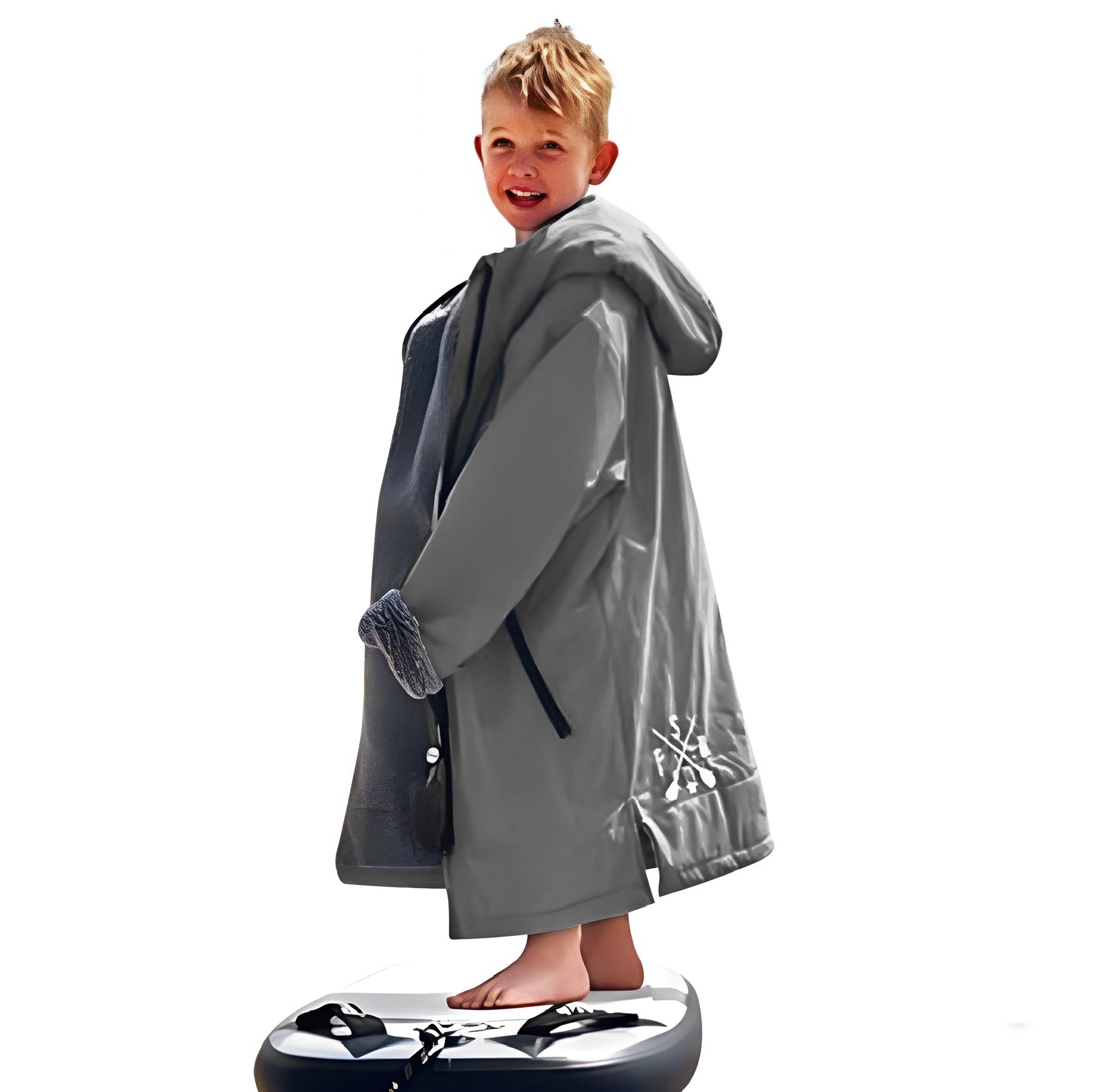 Young boy in grey FatStick Kids FatWrap changing robe with sherpa fleece lining, smiling, on paddleboard.