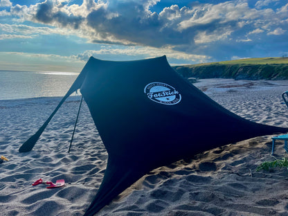Black Fatstick Beach Tent sun shade gazebo on a sandy beach overlooking the ocean.
