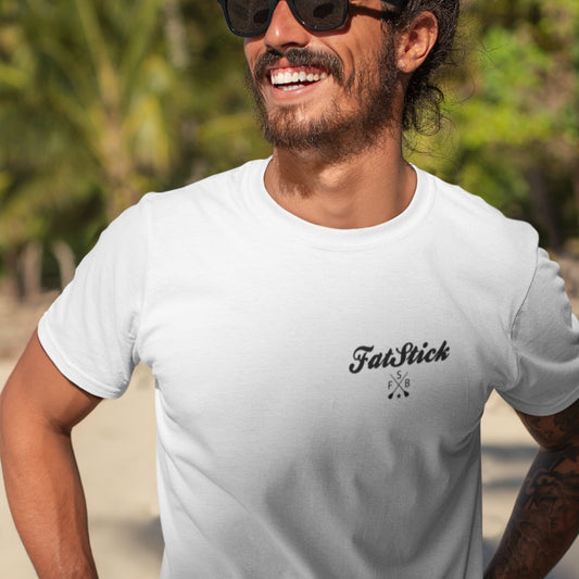 Man laughing wearing white FatStick South Coast Lifestyle T-Shirt and sunglasses, tropical beach background.