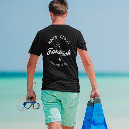 Man walking away on beach wearing black FatStick South Coast Lifestyle T-Shirt, holding snorkel gear.