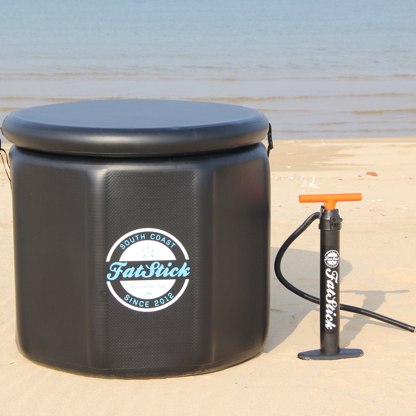 Round FatStick pro cold water therapy plunge tub on sand, with pump and closed top.