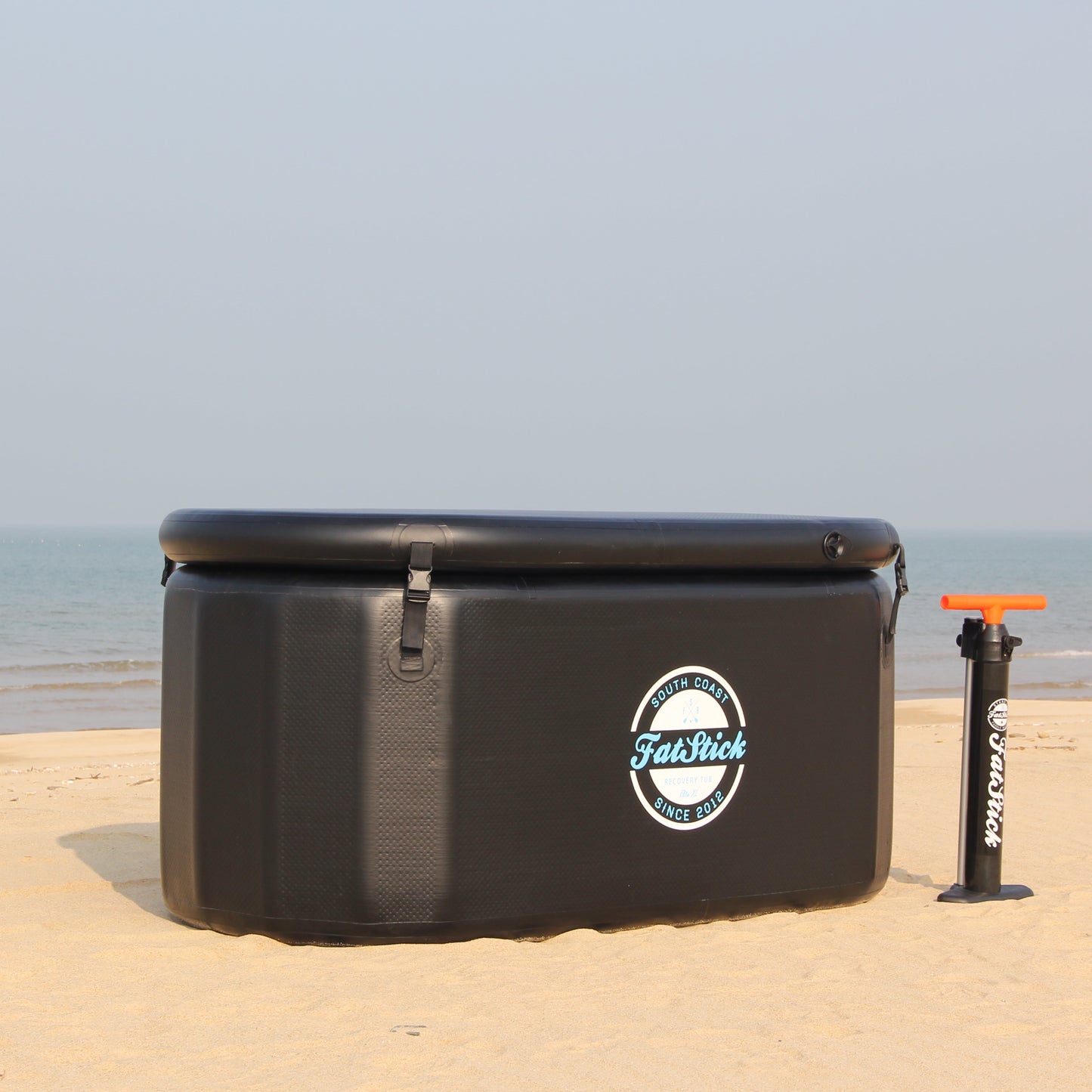 FatStick pro cold water therapy plunge tub, with pump on the beach, ocean in the background.