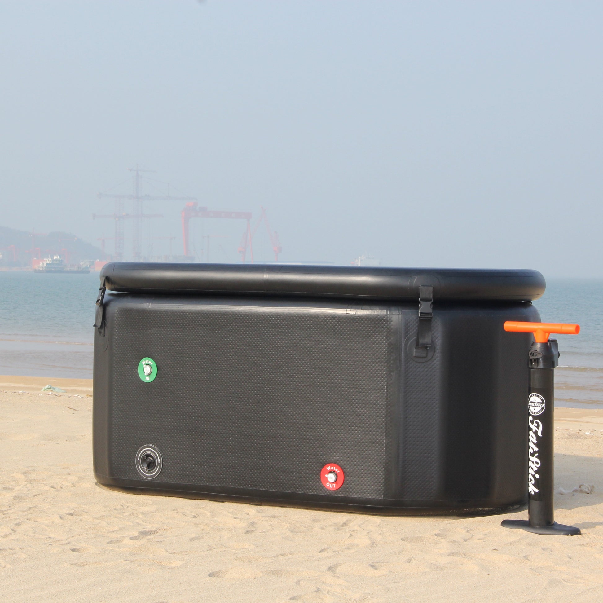 FatStick pro cold water therapy plunge pool and pump on a sandy beach, ocean in background.