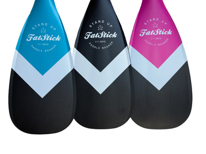 Three FatStick Boards full carbon paddle board paddles in blue, black, and pink with white chevron pattern.