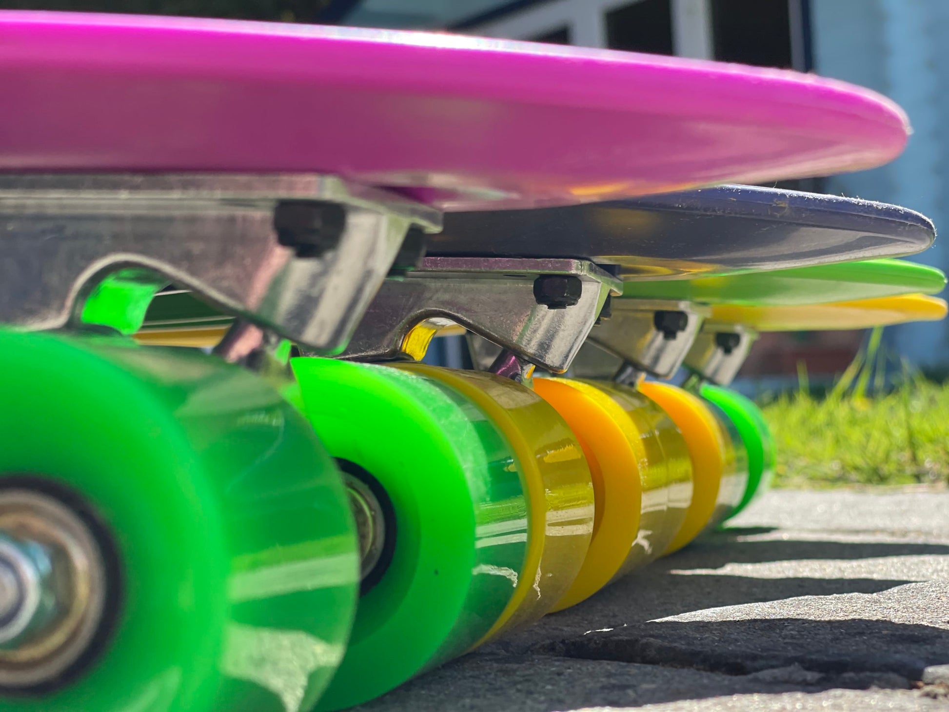 Close-up side view of four colorful FatStick Mini-Cruiser skateboards wheels and trucks