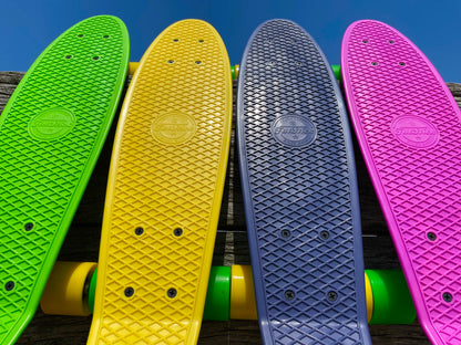 Upward view of four colorful FatStick Mini-Cruiser skateboards decks and wheels against blue sky