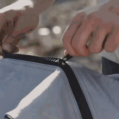 Close up action shot of hands zipping up the silver and black travel bag for the inflatable paddle board.