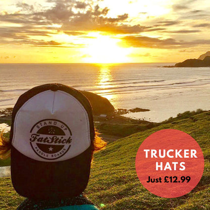 Rear view of a person wearing a FatStick Team Trucker Hat watching the sunset over the ocean