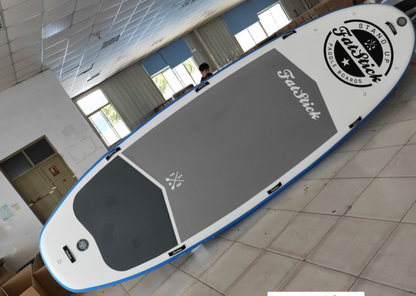 Overhead view of the XL Giant FatStick Paddle Board Package in a warehouse, showing the full deck with grey anti-slip pad and branding.